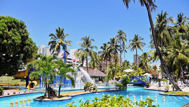 A resort pool area with multiple water features, palm trees, and lounge chairs. - Matsubara Acqua Park Hotel (Maceió)