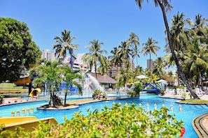 A resort pool area with multiple water features, palm trees, and lounge chairs. - Matsubara Acqua Park Hotel (Maceió)