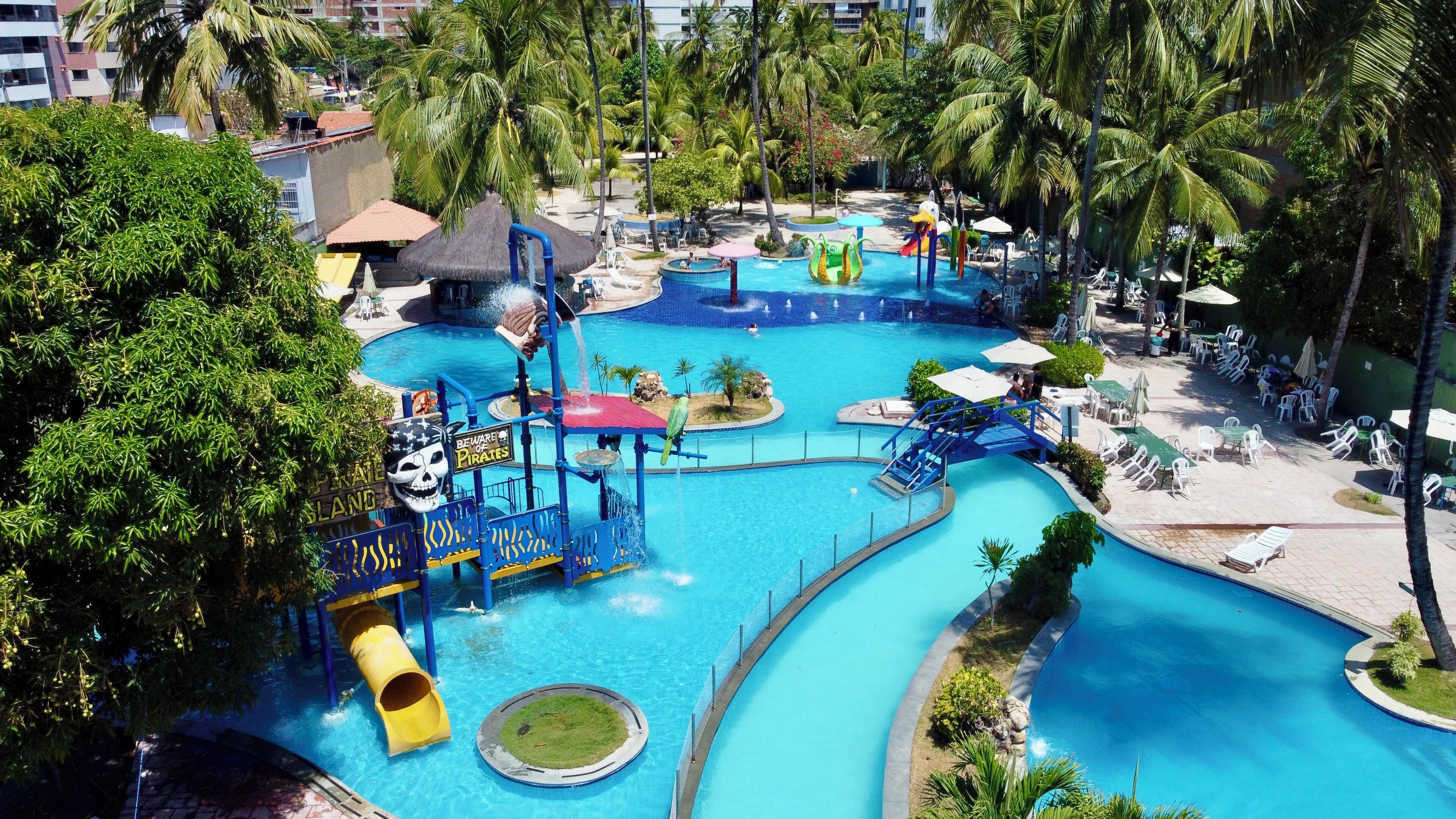 A water park with slides, pools, and palm trees.