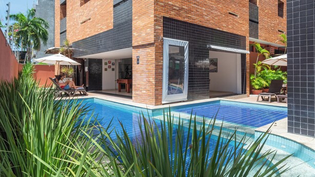 A modern building with a swimming pool, outdoor seating, and potted plants. - Ritz Plazamar Hotel (Maceió)