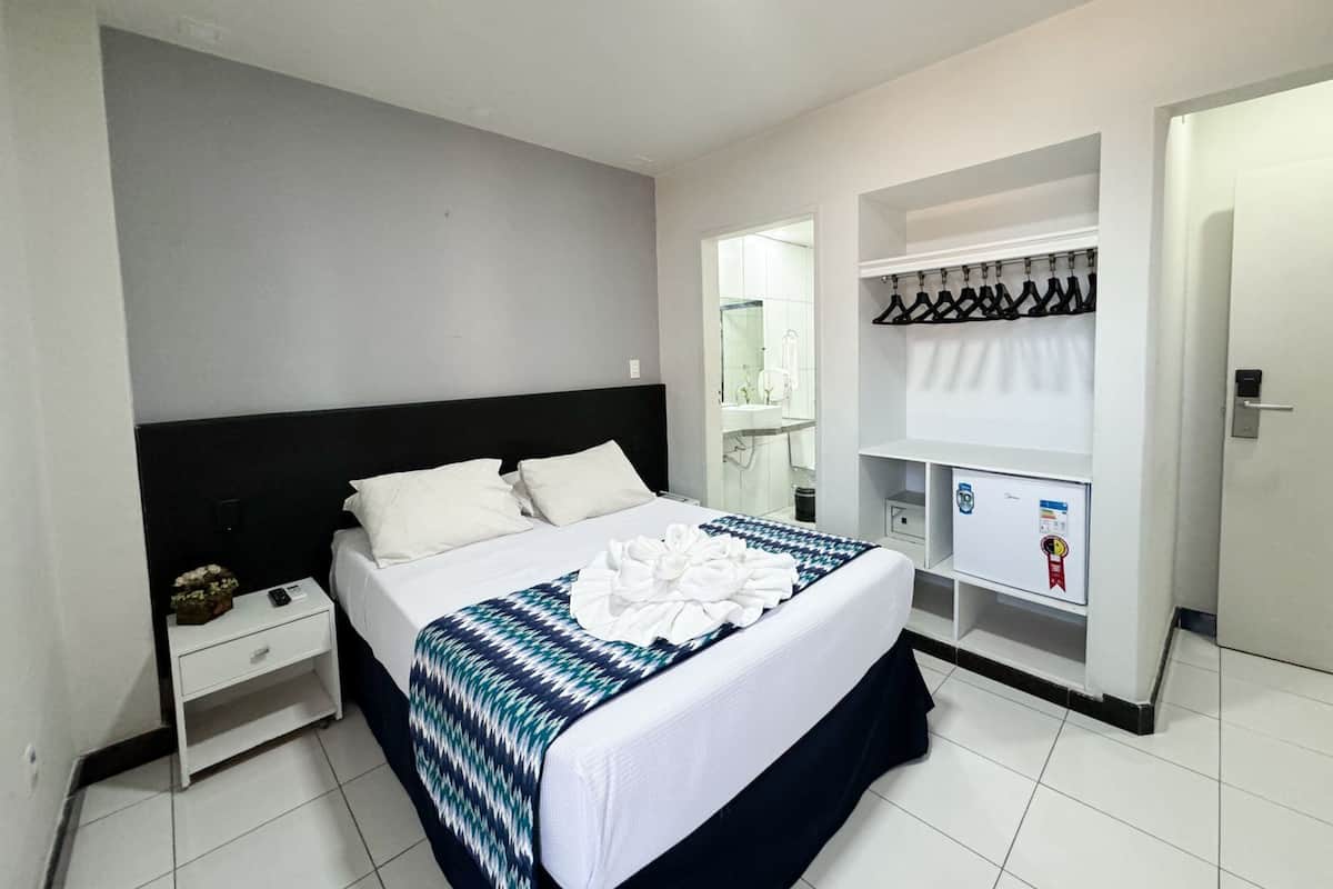 A hotel room with a bed, a nightstand, a wardrobe, and a mirror.