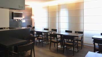 A modern restaurant with a bar area, multiple tables, and chairs.