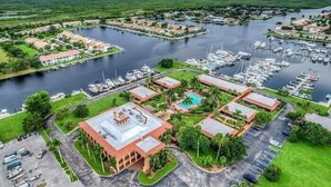 An aerial view of a marina with boats, a swimming pool, and buildings with a red roof.