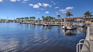 A marina with boats docked, palm trees, and a clear blue sky.
