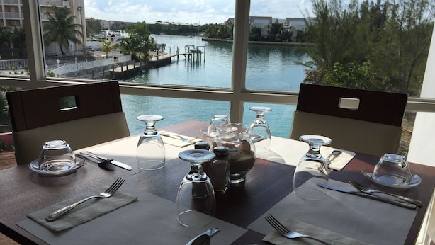 A table set for two with a view of a marina and buildings across the water. - Bell Channel Inn Hotel (Freeport)
