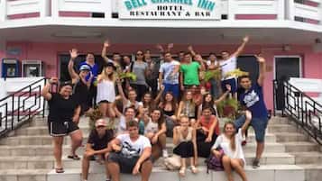 A group of people posing in front of a hotel named 'Bell Channel Inn' with a sign indicating it is a hotel, restaurant, and bar.