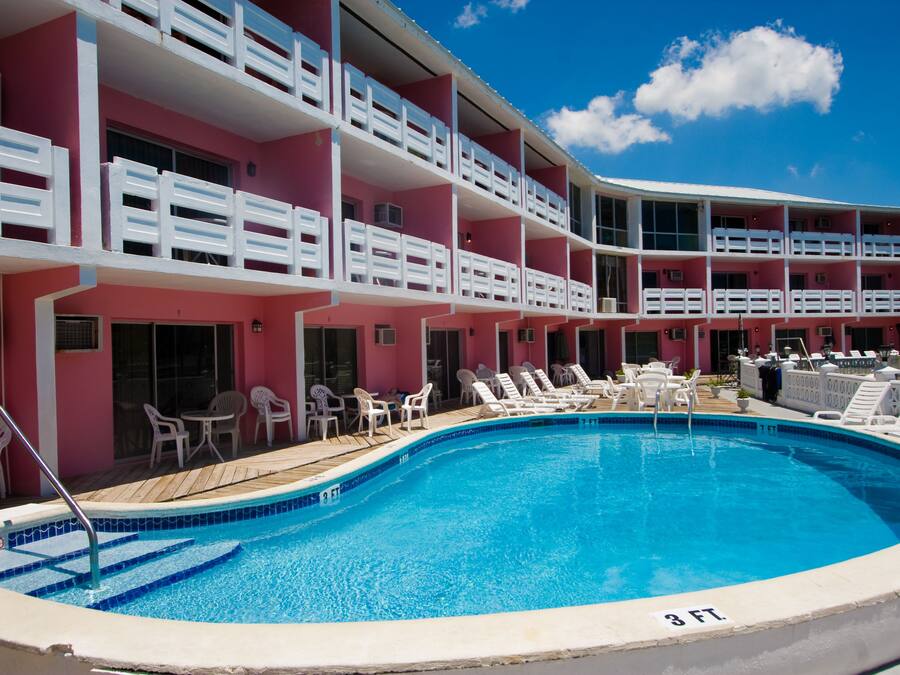 A hotel with a swimming pool surrounded by lounge chairs and a wooden deck.