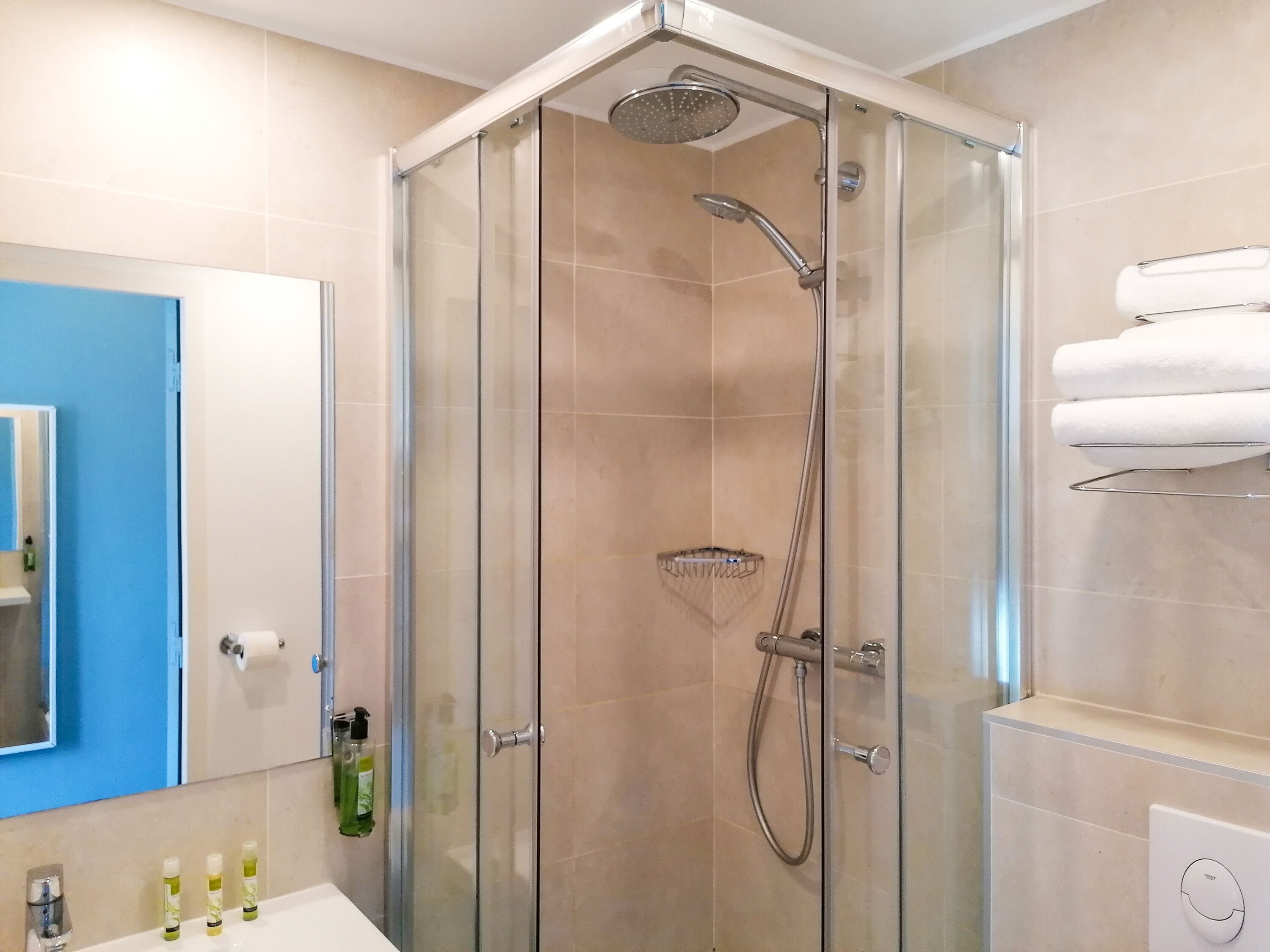 Un bagno moderno con doccia vetrata, porta asciugamani a vista e lavabo con articoli da toilette.