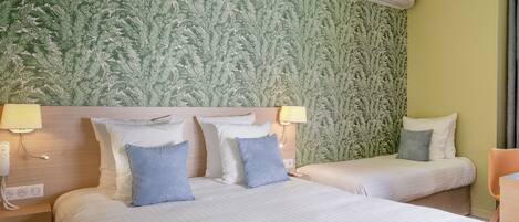 A hotel room with two beds, a green textured wall, and an air conditioning unit.