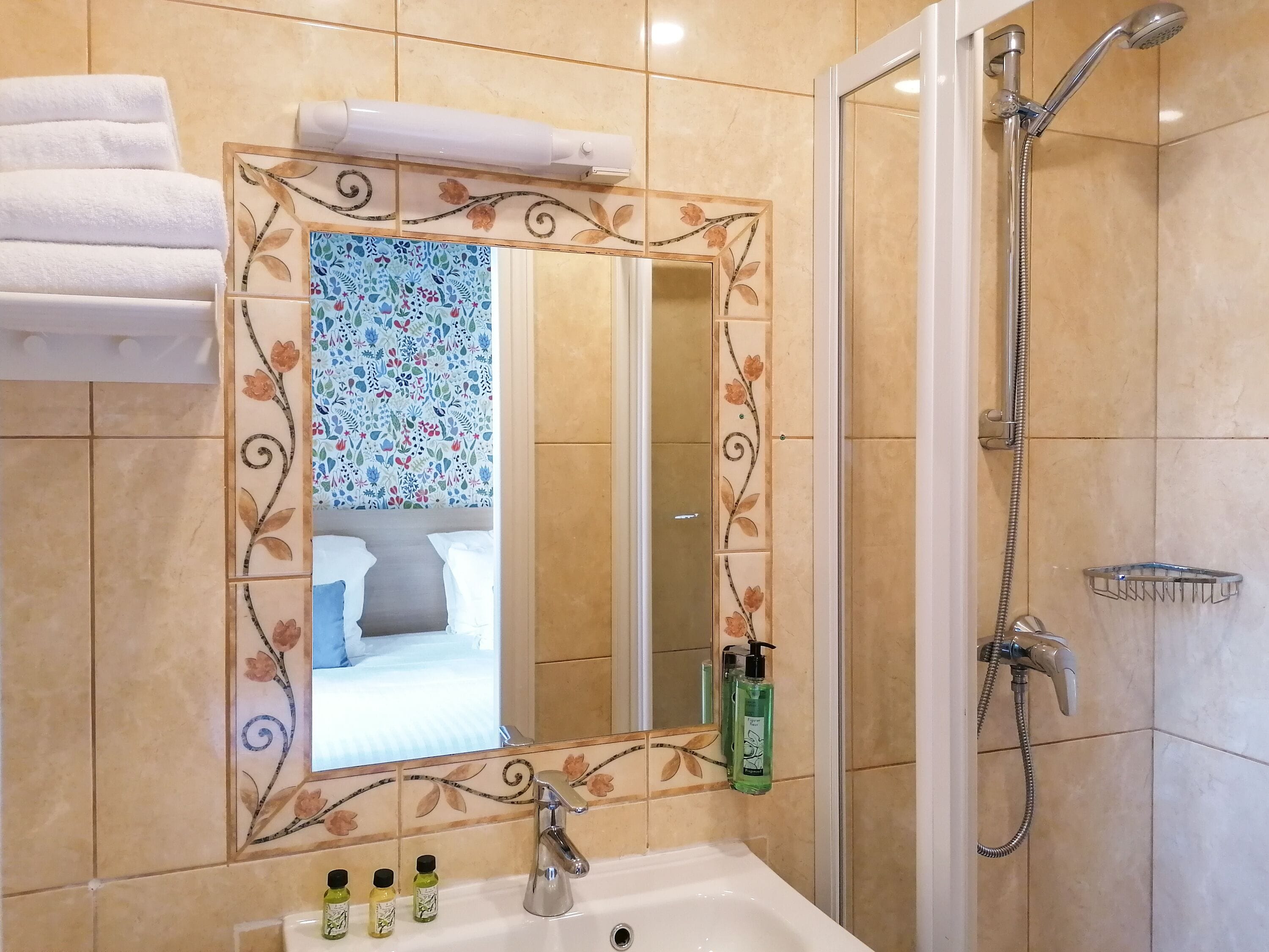 Une salle de bain avec un grand miroir, une douche et un lavabo équipé de produits de toilette.