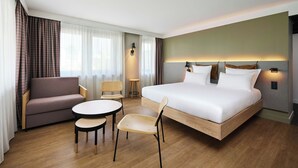 A hotel room with a bed, a sofa, a small table, and two chairs. - Moxy Annecy (Annecy)