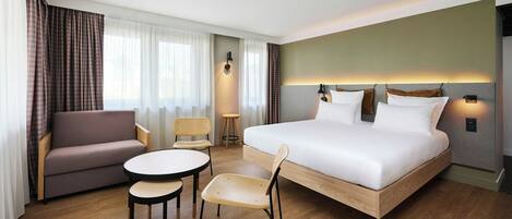 Una habitación de hotel con una cama, un sofá, una mesita y dos sillas.