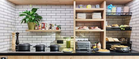 A kitchen with a black countertop, wooden cabinets, a hanging plant, and various kitchen appliances and utensils.