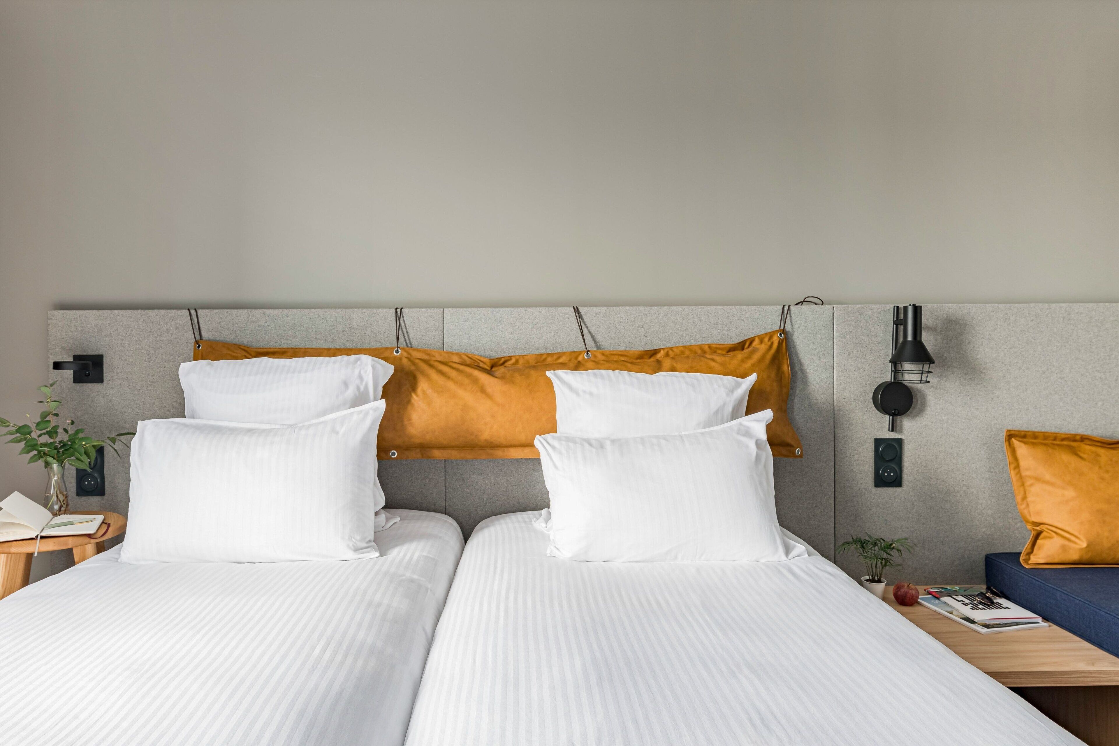 Ein Hotelzimmer mit zwei Betten, einem Nachttisch, einer Wandlampe und einer kleinen Pflanze.
