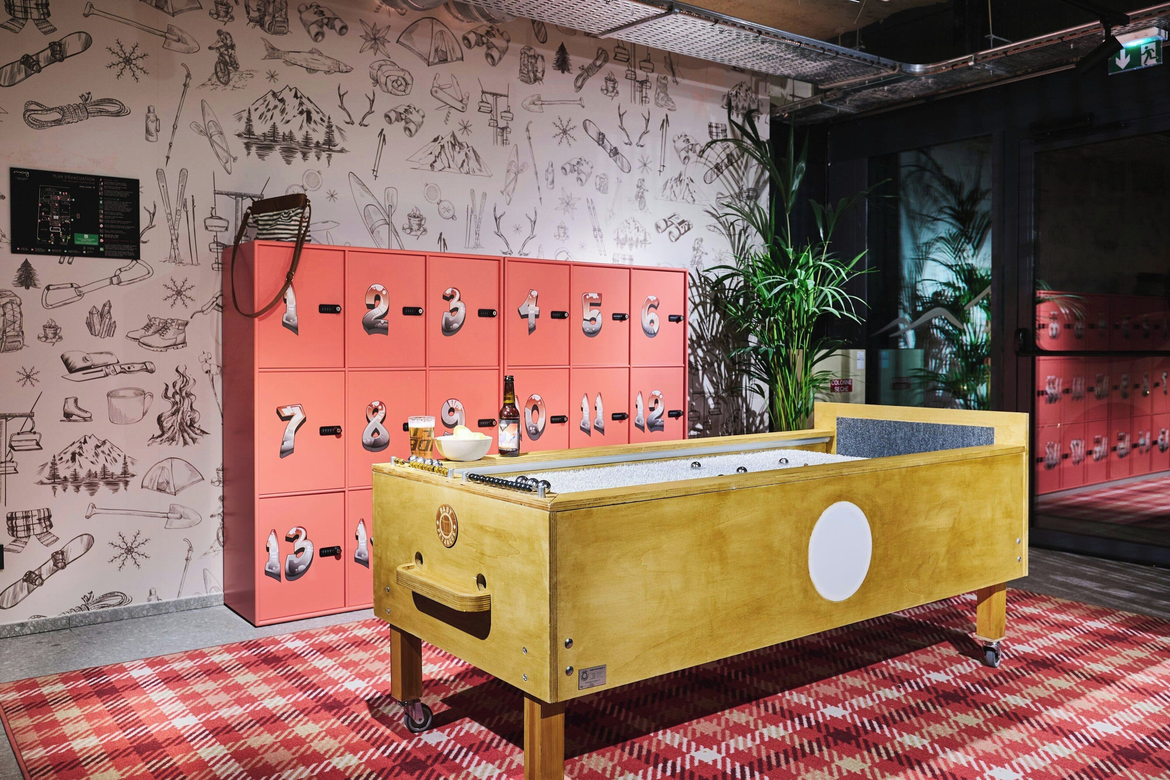 A room with a checkered red carpet, a wooden bed with a white circular design, a pink storage unit with numbered compartments, and a wall decorated with various doodles.