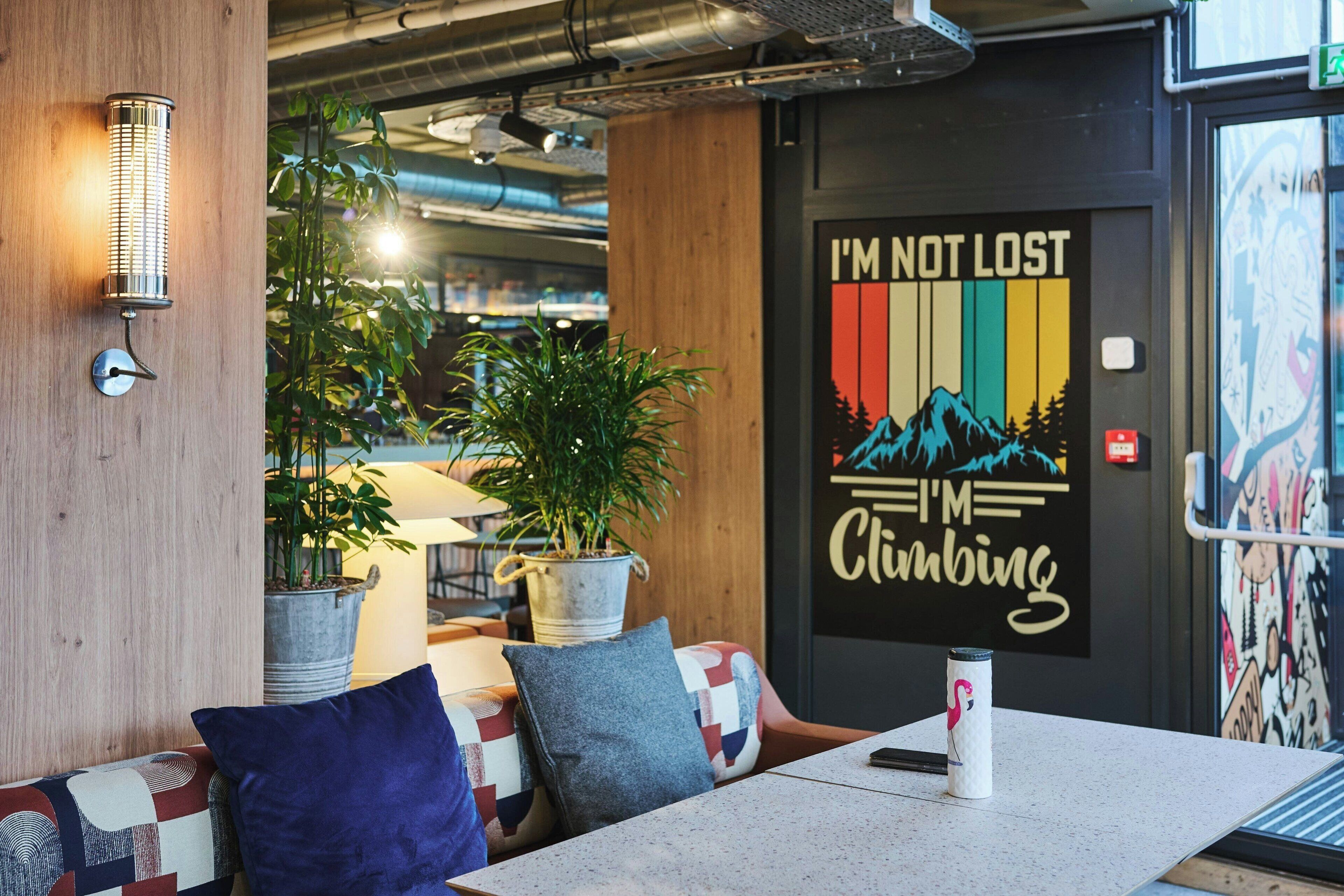 Un área de estar interior acogedora con una pared de madera, un aplique de metal y un mural con el texto "I'M NOT LOST I'm Climbing".