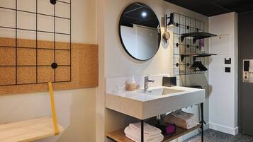 A modern bathroom with a large mirror, a sink, and a towel rack.