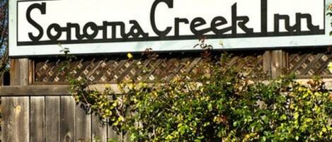 Placa do Sonoma Creek Inn, com uma cerca de madeira e uma árvore em primeiro plano.