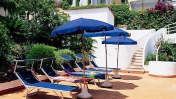 Un espace aménagé au bord de la piscine, avec des chaises longues et des parasols.