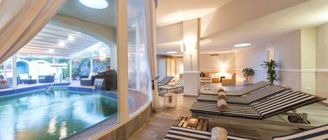 A spa area with a pool, sun loungers, and a view of a poolside area.