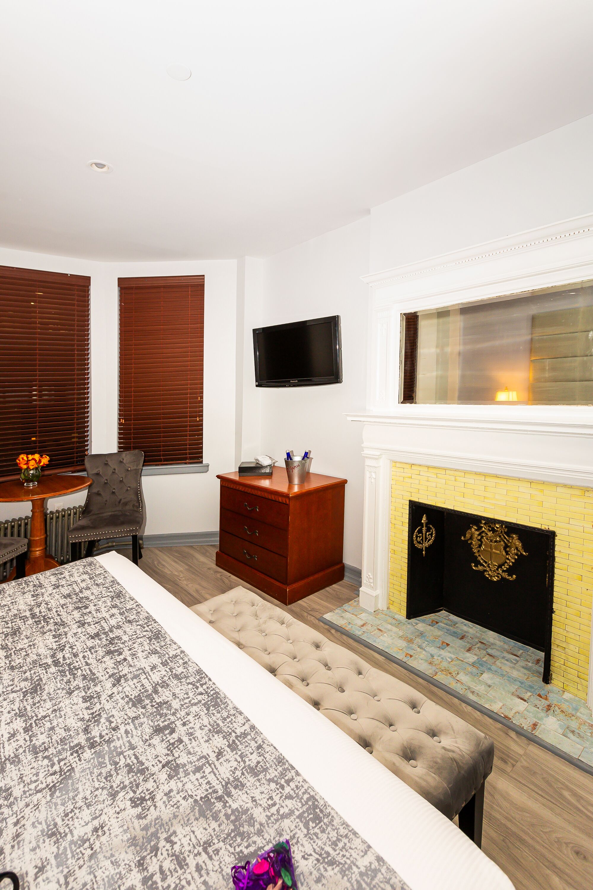 Habitación de hotel con cama, televisor montado en la pared, chimenea y escritorio con silla.