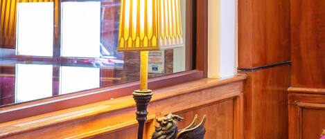 Een houten bureau met een lamp, een decoratief beeldje en een paarse stoel.