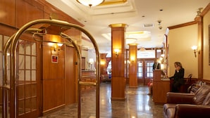 A lobby with a reception desk, a red carpet, and a brass elevator. - Hotel St. James (New York)
