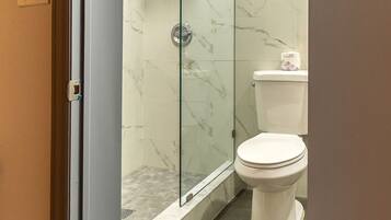 Un baño con ducha de vidrio, inodoro y perchero para toallas.