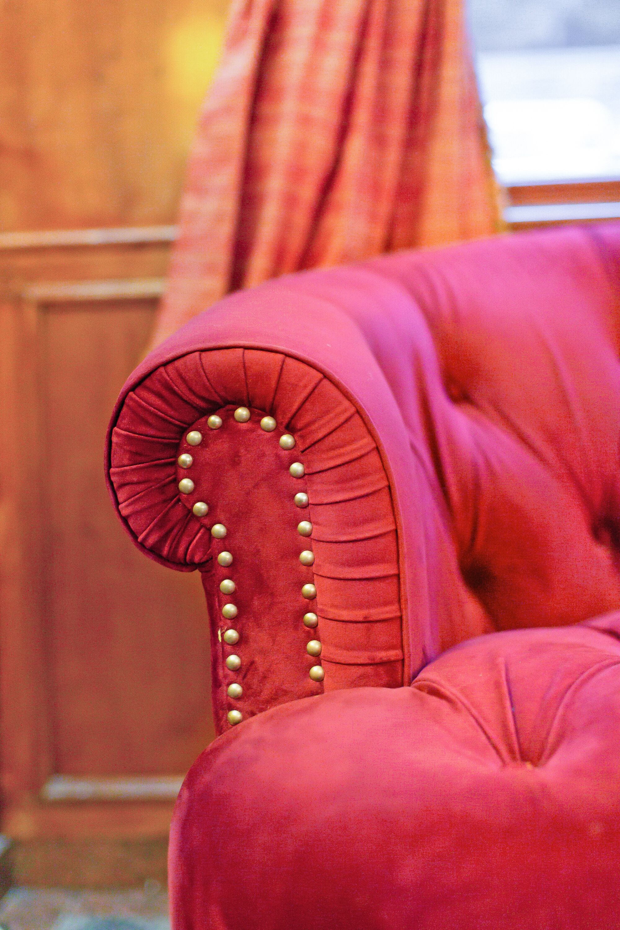 A close-up of a red upholstered chair with a tufted backrest and decorative buttons.