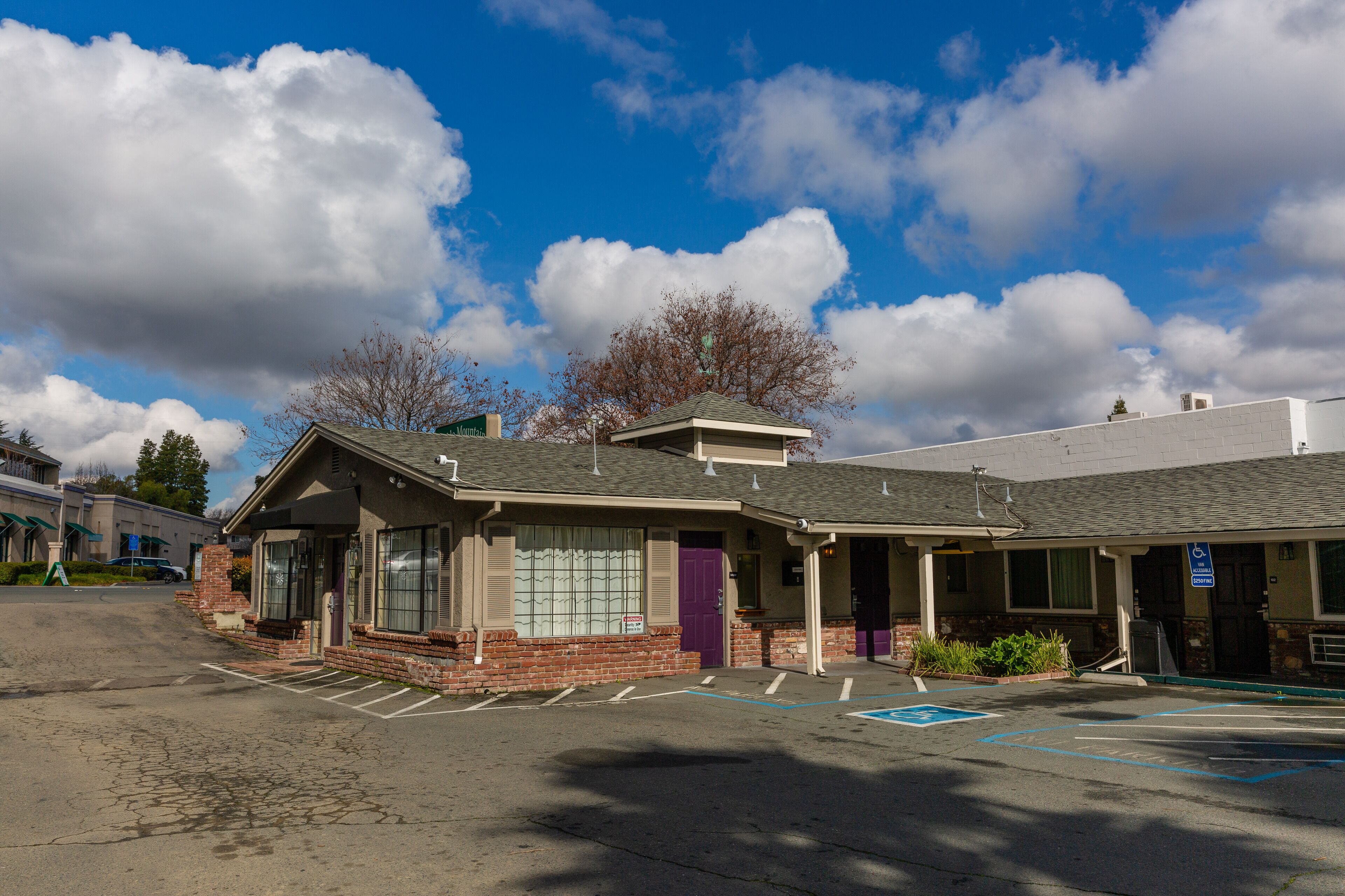 A building with a parking lot, a purple door, and a sign indicating handicap accessibility.