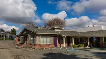 A building with a parking lot, a purple door, and a sign indicating handicap accessibility.