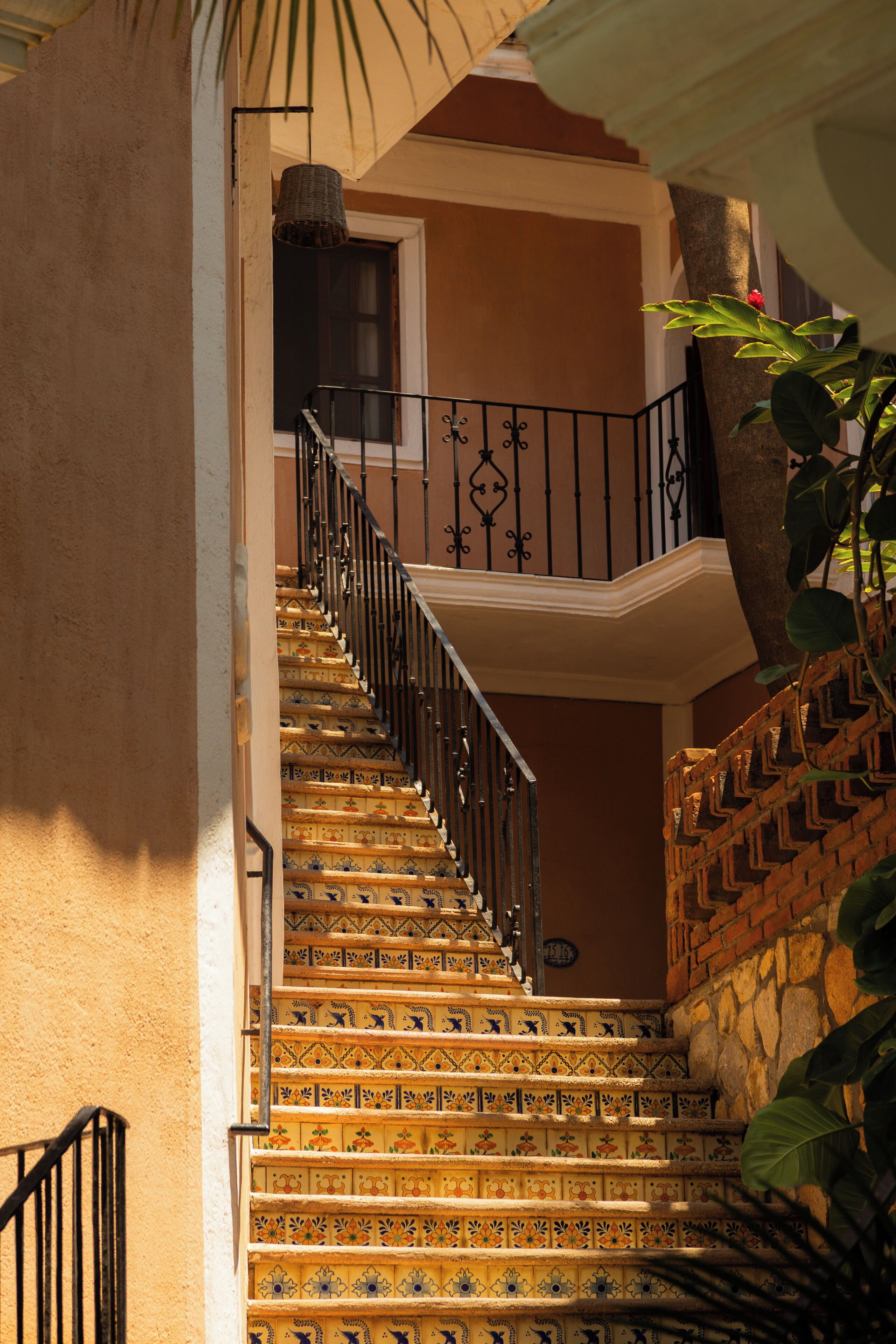 Un escalier orné de carreaux décoratifs, une rampe en fer forgé et un mur en briques.
