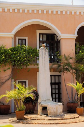 A building with a central column, potted plants, and a bench. - Hotel Santa Fe (Puerto Escondido)