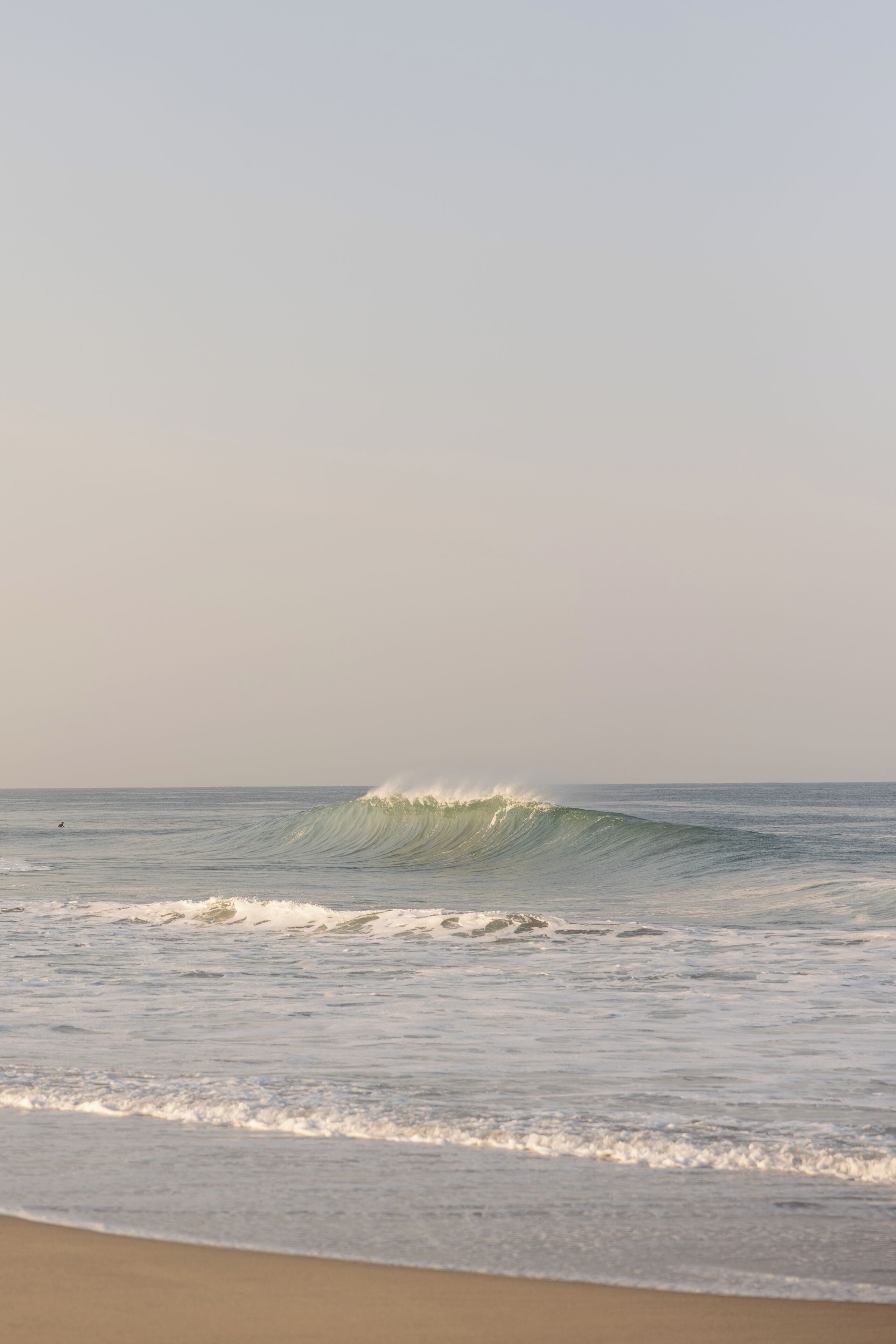 A beach with waves and a clear sky.