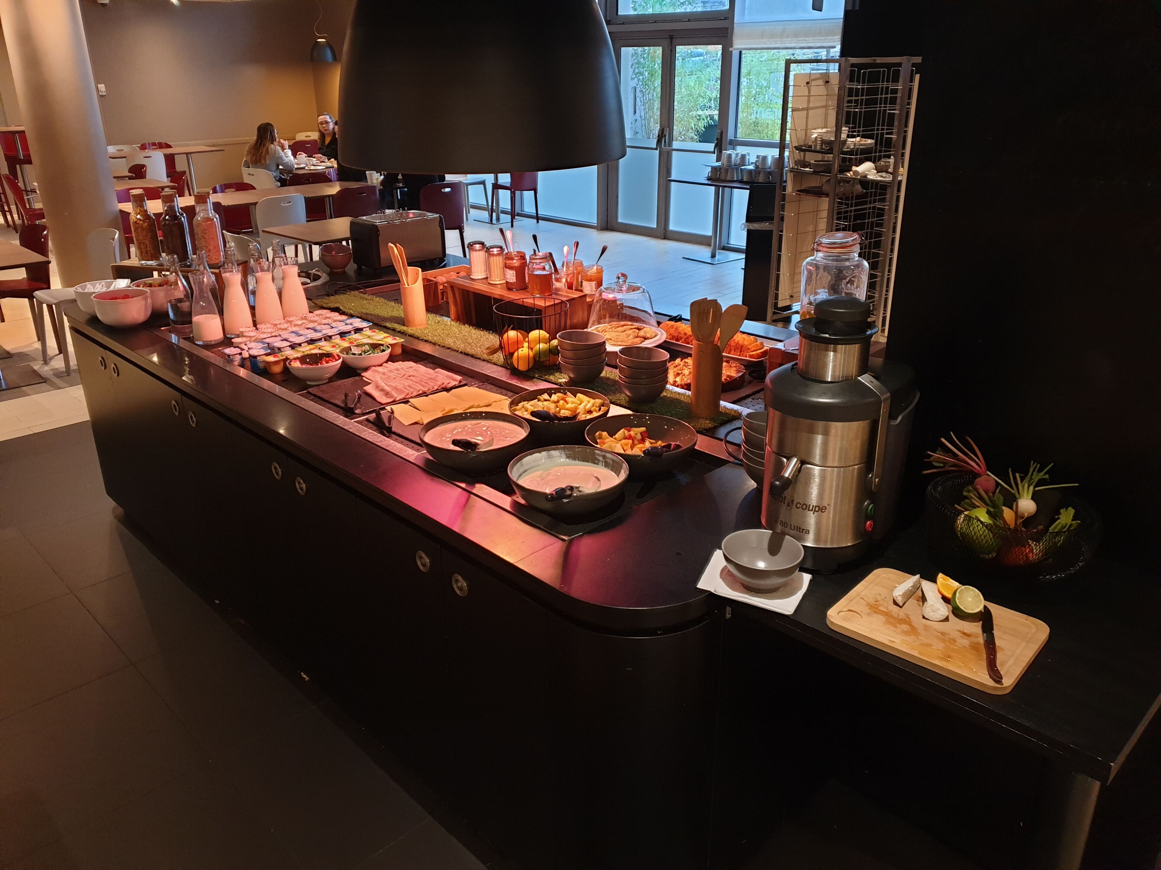 A buffet with various food items and condiments, a coffee machine, and a fruit basket.