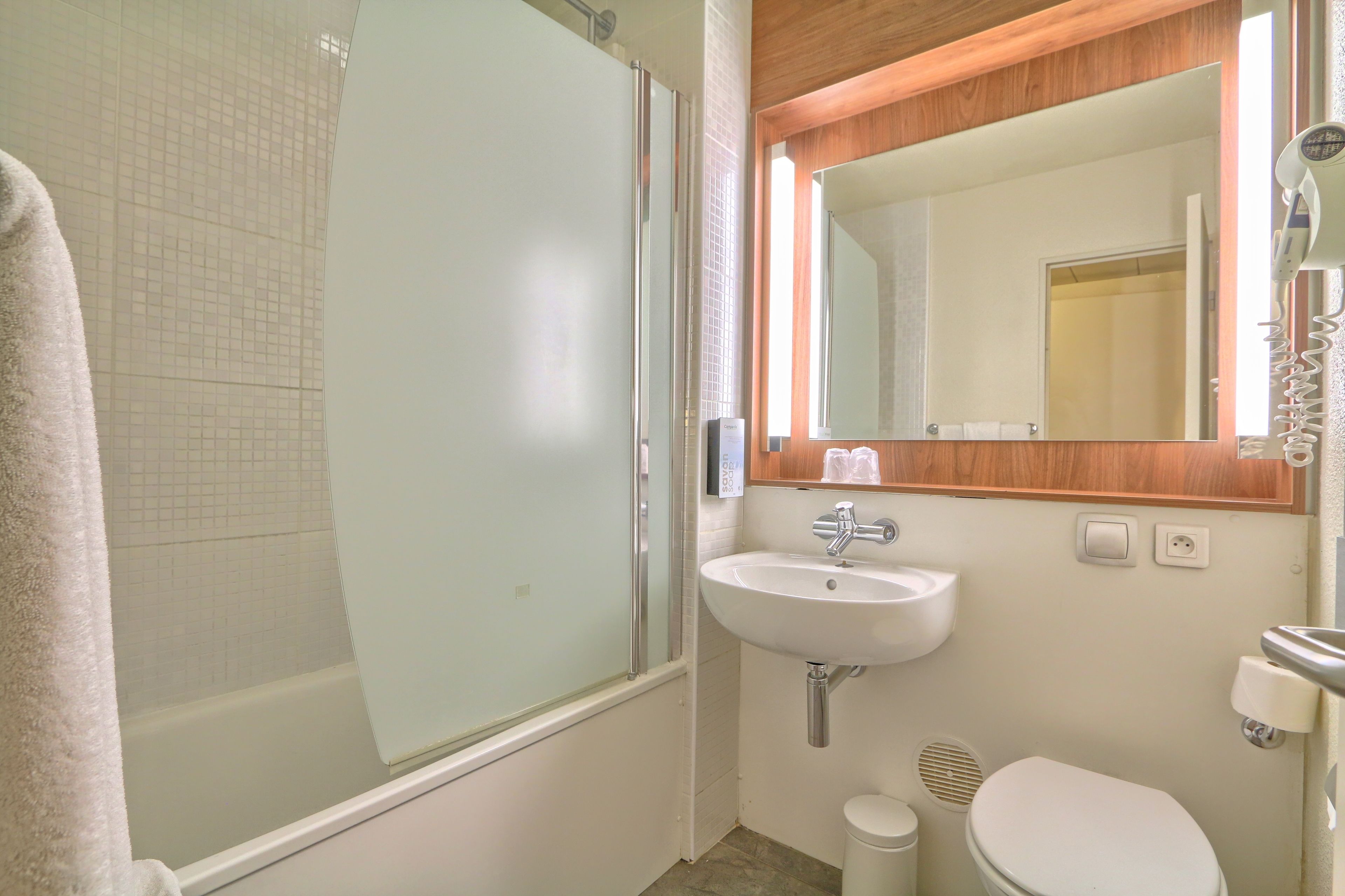 Une salle de bain avec une douche à parois de verre, un lavabo, des toilettes et un miroir au-dessus du lavabo.
