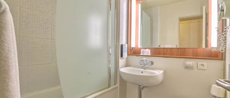 Une salle de bain avec une douche à parois de verre, un lavabo, des toilettes et un miroir au-dessus du lavabo.