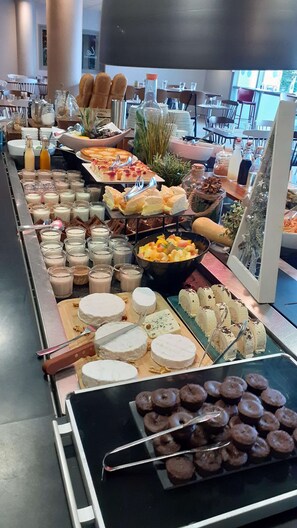A buffet with various food items including pastries, cheeses, and fruits.