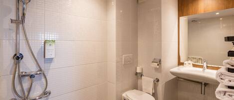 Un baño con ducha, inodoro, lavabo y espejo.
