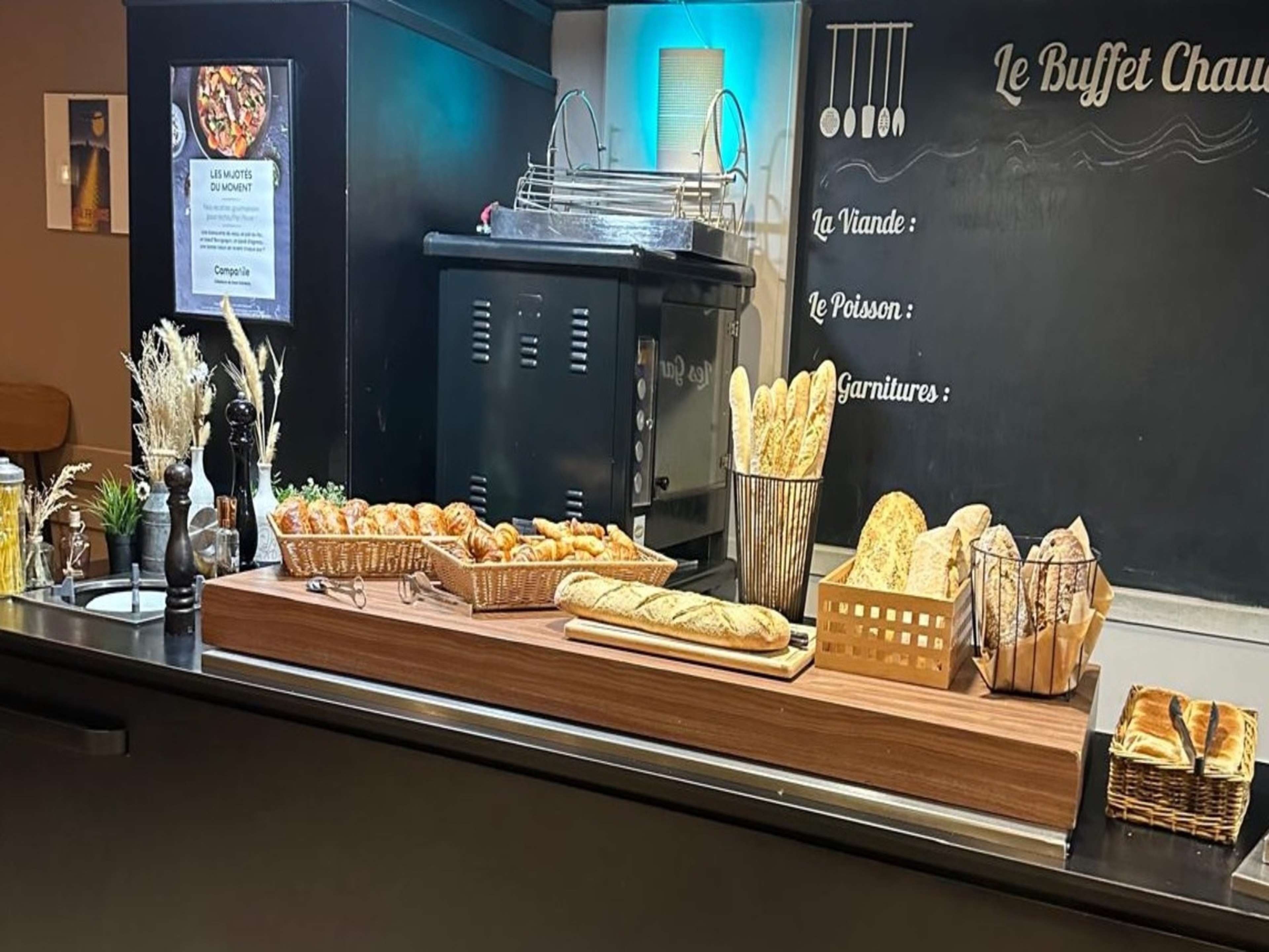 A buffet counter with various bread and pastries displayed in baskets and on a wooden board.