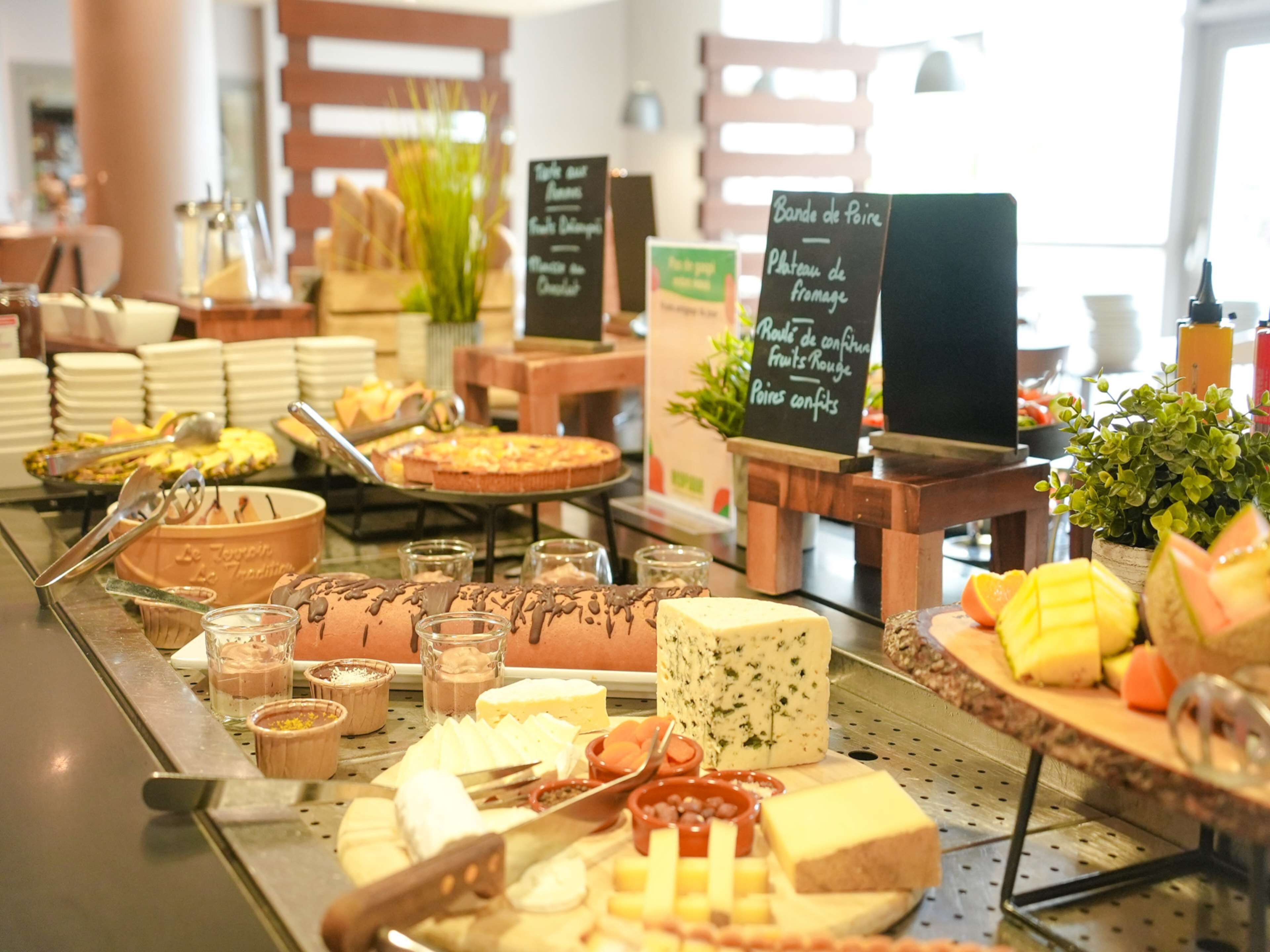 Un bufé con diversos quesos, frutas y postres.