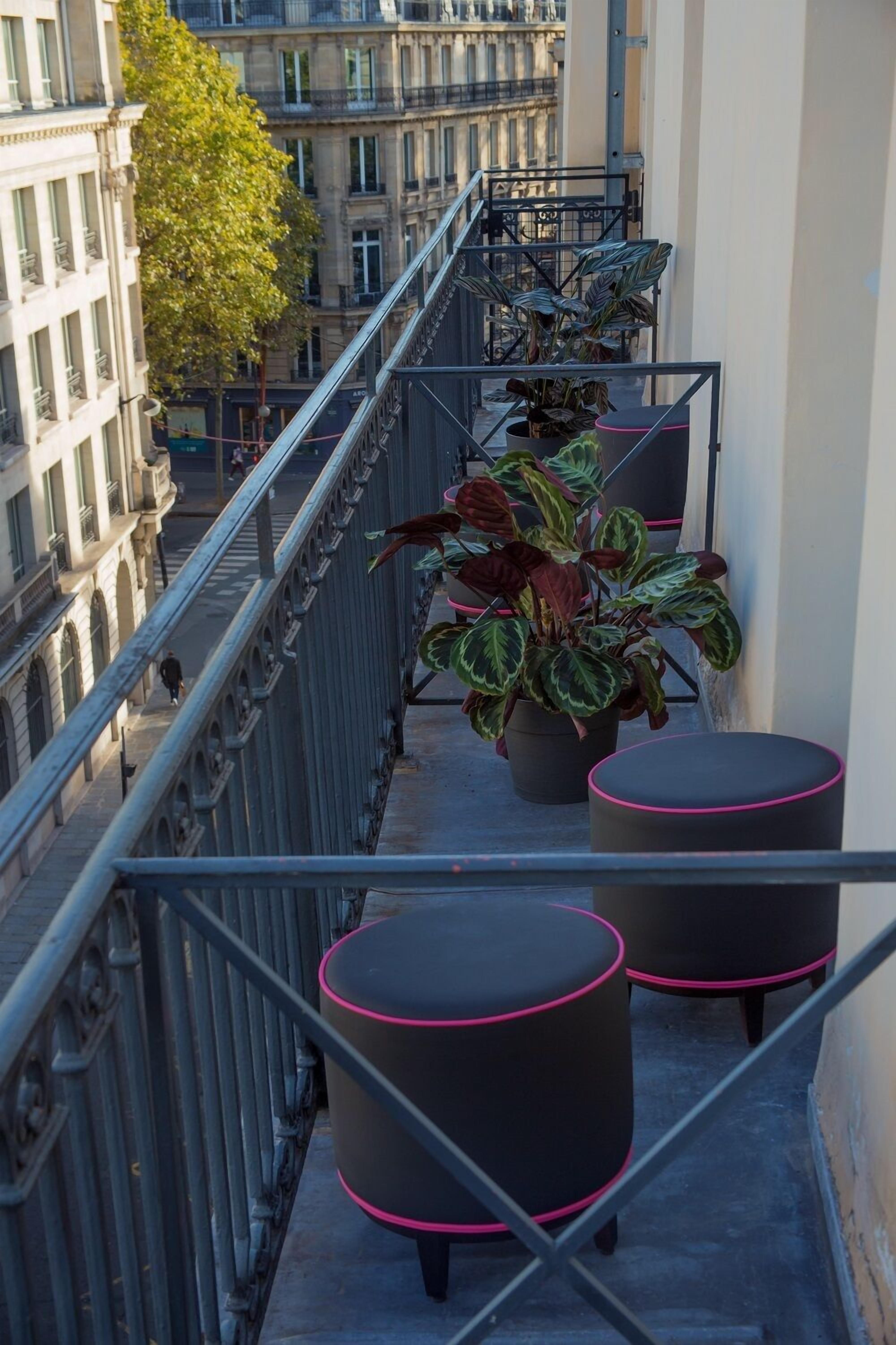 Een balkon met potplanten en ronde tafels.