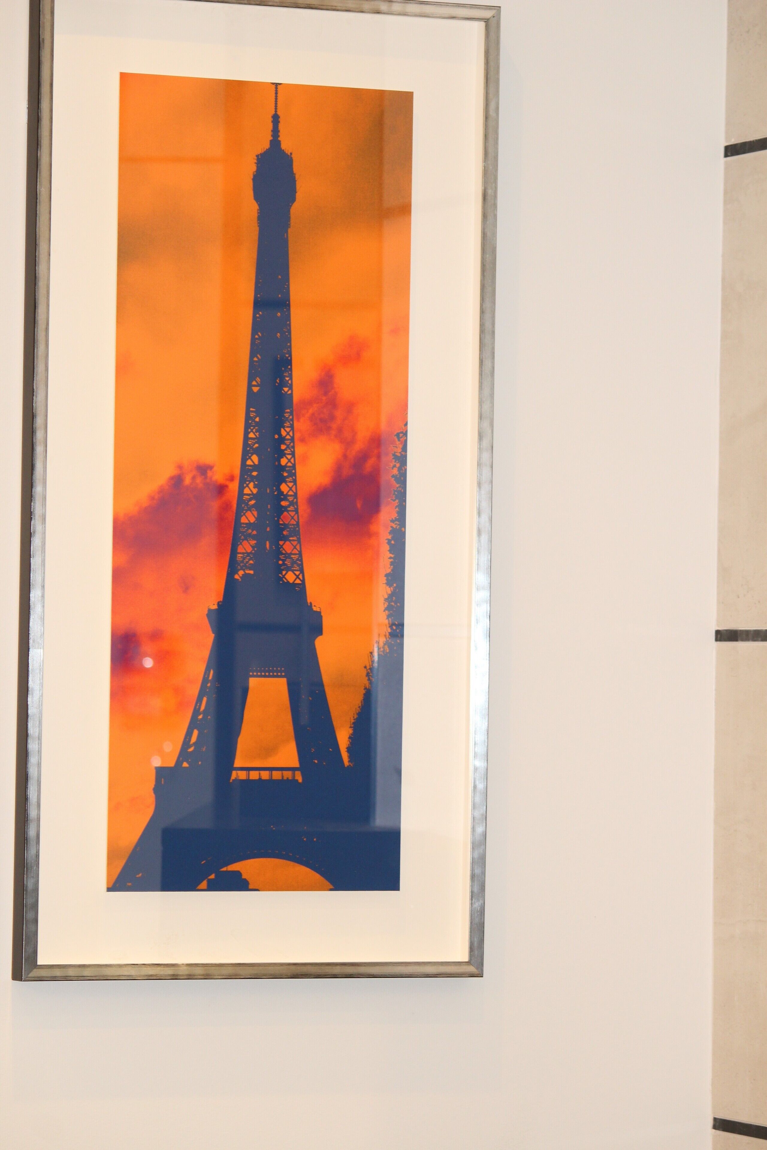 A framed picture of the Eiffel Tower against a sunset backdrop.
