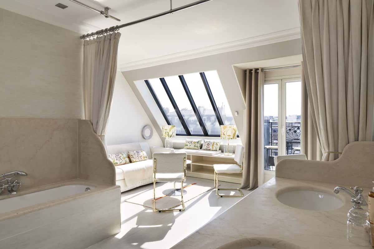 A modern bathroom with a large bathtub, a sink, and a skylight.