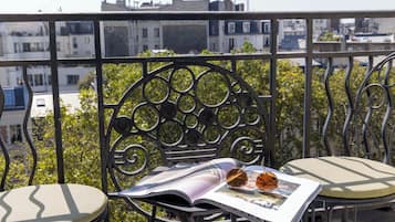 Ein Balkon mit Metallgeländer, einem Stuhl, einem Kissen und einer Zeitschrift mit Sonnenbrille darauf.