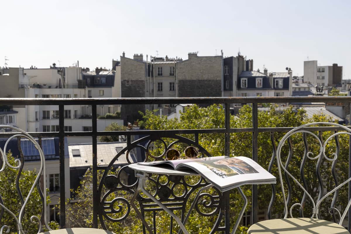 A balcony with a metal railing, a chair, and a magazine.