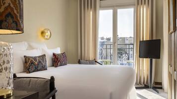 A hotel room with a large bed, a television, a balcony with a view of the city, and a decorative lamp.