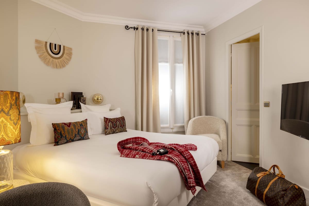 A hotel room with a large bed, a chair, a TV, and a door.