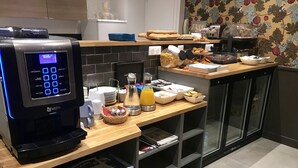 A modern kitchen with a coffee machine, breakfast items, and a tiled backsplash. - Hotel Excelsior Batignolles (Paris)