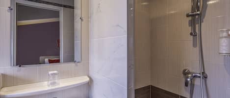 A bathroom with a white sink, mirror, and shower.